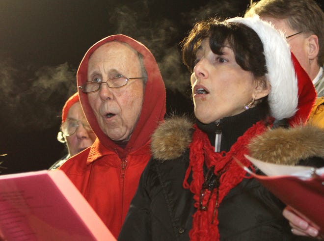 With their breath hanging frozen in the air, Millis residents Brooks Corl and Carolyn McNiff share a book as they perform Christmas carols at Medway Common Plaza on Thursday evening. Members of St. Joseph's Choir and Charles River Chorale held the fundraiser to support next year’s Christmas parade and holiday festivities administered by the town-appointed Medway Christmas Parade Committee. The parade this year drew 6,000 participants.