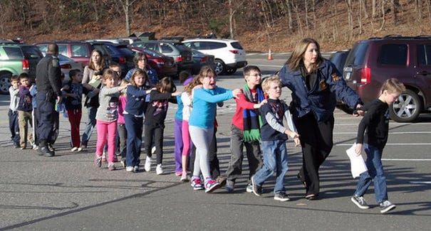In this photo provided by the Newtown Bee, Connecticut State Police lead children from the Sandy Hook Elementary School in Newtown, Conn., following a reported shooting there Friday, Dec. 14, 2012. (AP Photo/Newtown Bee, Shannon Hicks)