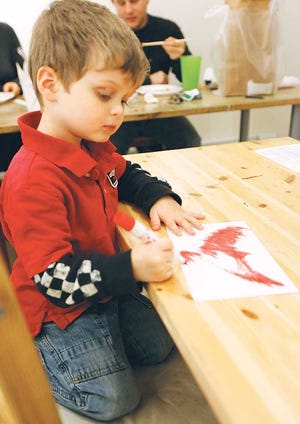 Photo by Tracy Klimek/New Jersey Herald Four-year-old Joel Goldberg colors in a paper dove in his mother Jennie Schaeffer’s store, TraillWorks art studio, in Newton Friday to hang in one of the participating Spring Street store windows.