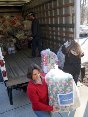 Lori Smith of Sanofi Pasteur totes a large bag of gifts on Friday from a truck at Pocono Services for Families and Children in East Stroudsburg. The gifts were donated by the staff at Sanofi Pasteur as part of their Adopt-a-Family drive. The Adopt-a-Familiy program will help 31 Monroe County Head Start families this year. This is the 18th year that Sanofi Pasteur has donated gifts.
