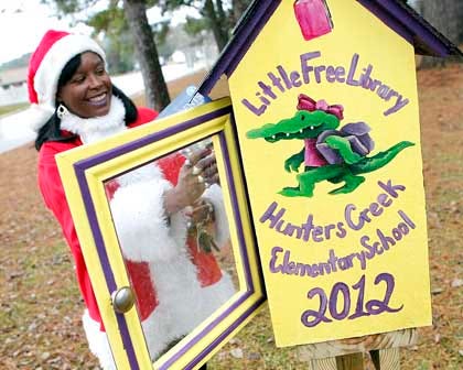 Mary Dwyer, principal of Hunter's Creek Elementary school, places holiday books in the Little Library at Holiday City Mobile Home Community in Jacksonville.