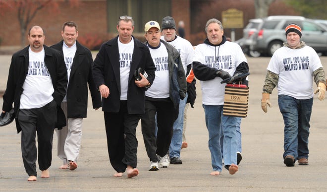 Dino Costi (second from right) led a group of volunteers on a 1.2 mile walk from Arrowhead Golf Club to Mullinax Ford located in North Canton. The mostly barefoot volunteers walked to raise awareness about the charity "Until You Have Walked a Mile" formed earlier this year. "Until You Have Walked a Mile" collects and distributes shoes to area social service agencies and religious groups. The have provieded 400 pairs of shoes to groups like the Domestic Violence Project, Total Living Center and Refuge of Hope. Costi said there is a need for childrens shoes. Donations can be made at Mullinax Ford, 5900 Whipple Avenue.