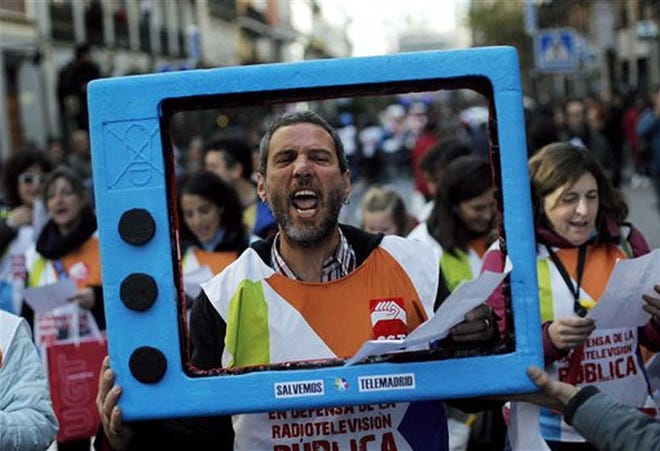 CROSS SIGNAL — A protester shouts slogans though a fake TV during a demonstration against the dismissal of 925 workers announced by the public TV ’Telemadrid’ Saturday in Madrid, Spain.