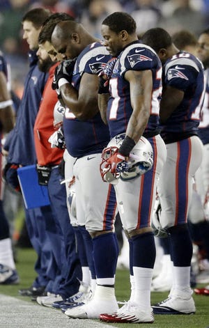 Vince Wilfork, left, and Tavon Wilson join their Patriots teammates during a moment of silence for the victims of Friday's Sandy Hook Elementary School shootings in Newtown, Conn., before Sunday night's game against the 49ers.
