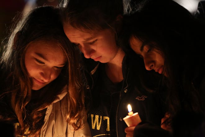 Kate Suba, left, Jaden Albrecht, center, and Simran Chand pay their respects at one of the makeshift memorials in honor of the victims of the Sandy Hook Elementary School shooting, Sunday, Dec. 16.