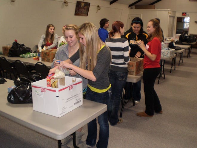 Pellston National Honor Society students gather at St. Clement Catholic Church Tuesday to assort food and gift items that will be distributed to families in need before the holidays.