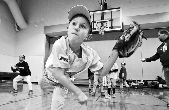 John Gaines/The Hawk Eye Nathan Parks, 8, with the Iowa River Rippers, a 9-year-old-and-younger youth baseball team, follows through in a throwing drill Wednesday inside the gym at Corse Elementary School in Burlington. The team started in December and will use the inside facilities until the warmth of spring when games begin in April.