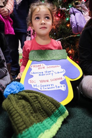 Medway Shining Stars Nursery School student Brianna Leland, 4, holds a hat and a card that will be presented with donated mittens and hats to students at Medway's McGovern Elementary School who are in need.