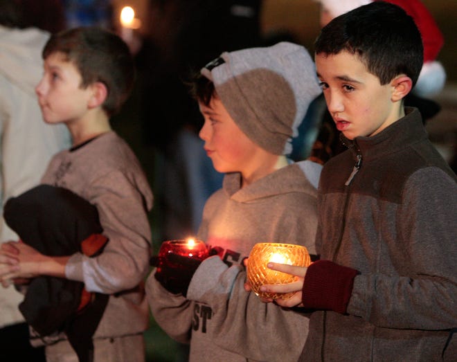 Joe Mcgahan, 10, from right, of Whitman; Braden Kain, 8, of Whitman; and Aiden Shea, 10, of Bridgewater join about 500 people holding candles and lining the pond at Whitman Town Park on Thursday night for a vigil honoring the victims of the Newtown, Conn., school shooting.