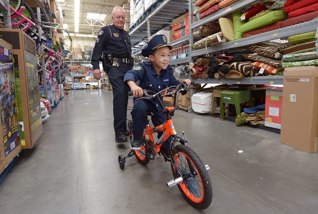 Chase Bowman, 5, tries out a new bike while shopping with Burlington Police Department retired Sgt. Greg Turner during the Cops Care event at Walmart on Graham-Hopedale Road on Friday.