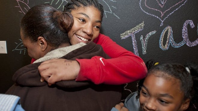 Delashai Clark, 14, gives her mom, Jamie Yancy, a big hug after seeing the family’s completely redone home in Round Rock on Thursday. At lower right, Nina Cousins, 8, is delighted about the chalkboard wall in the game room. Amplify Credit Union redid the house for the family as part of Season for Caring.