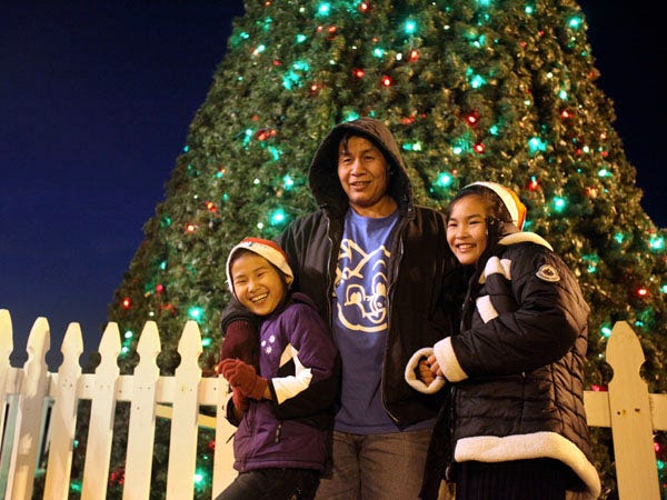 Eh Nay Say poses with daughters Eh Wah Say, 8, left, and Paw Wah, 11, in front of the Christmas tree in Riverfront Park in downtown Wilmington Friday, December 14, 2012.