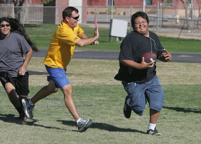 Tristan Torrez, left, PE teacher Kurt Kieser and Euginio Corral play a game of touch football in Kieser's PHAT class Friday Dec. 7, 2012 at Casa Grande Union High School in Casa Grande, Ariz. The students and teacher have lost a total of 120 pounds since Aug. 9.(AP Photo/Casa Grande Dispatch, Oscar Perez)