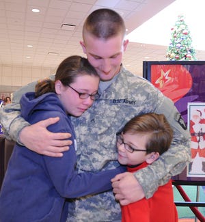 Jeffrey Miller, 19, center, returned home from Fort Campbell, Ky, to surprise his brother Charles, 7, right, and Holly, 11, left, of Brockton, at the Westgate Mall, on Saturday, Dec. 22, 2012.