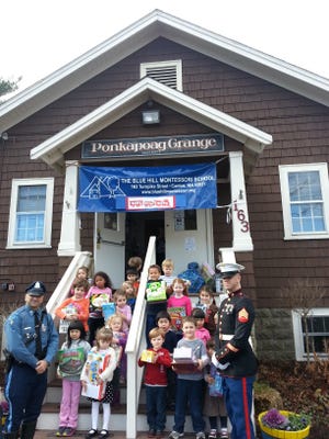 Children at Blue Hill Montessori School of Canton deliver their items to Toys for Tots representatives.