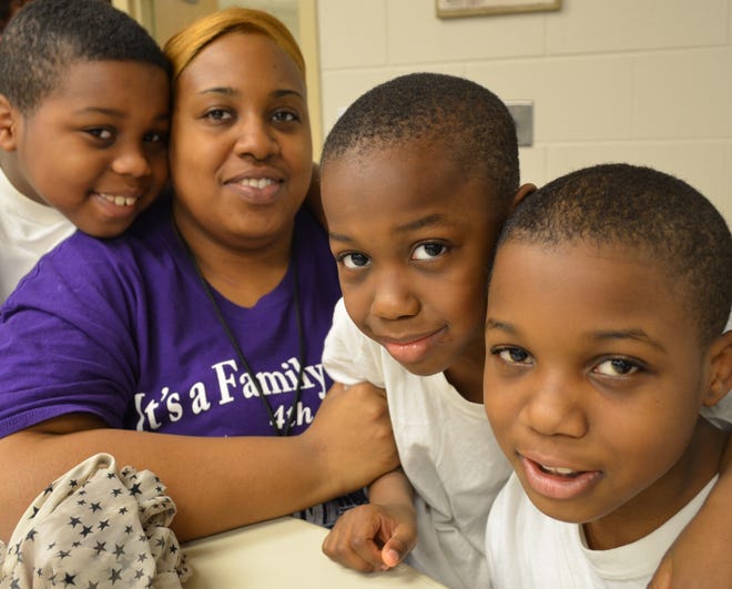 Tamara Mitchell, 30, with her three sons: Brendon Toliver, 10, Jacob Toliver, 9, and Archie Mitchel, 7 — Christmas morning at Holland Family Hope Ministry Center. Mitchell said she and her sons fled a violent home situation on Chicago's south side Friday. A family member suggested Holland as a safer home base. Peg McNichol/Sentinel Staff