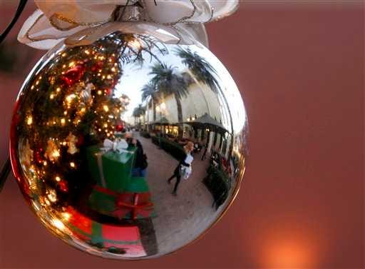 Holiday shoppers are reflected in a ornament handing from a large Christmas tree Dec. 20 at Fashion Island shopping center in Newport Beach, Calif.