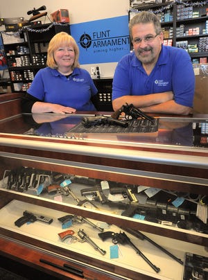 Karen and Roger Choquette stand behind the counter at their store, Flint Armament. The two handguns on the counter are manufactured by Smith & Wesson, based in Springfield.