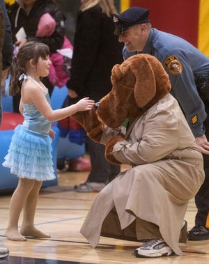 Five-year-old Laura De Las Heras of Middletown gets a high five from McGruff the Crime Dog during the annual First Night Newtown New Year's Eve celebration at Council Rock High School North on Monday evening. Also pictured is Newtown Township Police Officer Shawn Pirog.
