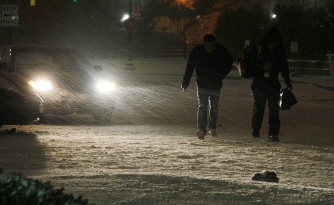Two pedestrians march through the cold wind and snow Thursday evening near the Renaissance Hotel in Providence.