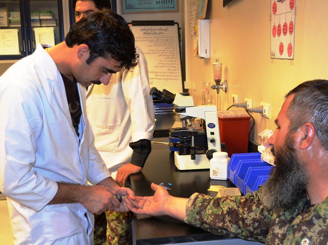 A lab worker at the Kandahar Region Military Hospital tests the blood of an Afghan National Army soldier.