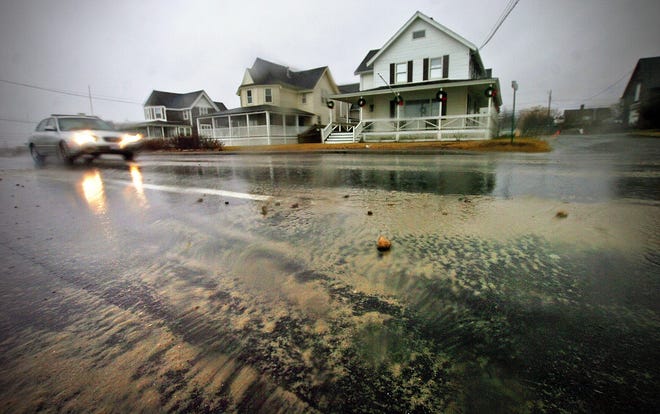 Rocks and sand that have blown ashore in recent storms cover Ocean Street in Marshfield on Friday, Dec. 21, 2012. Higher sea levels, which some attribute to global warming, have contributed to flooding in this part of town during many storms in recent years.