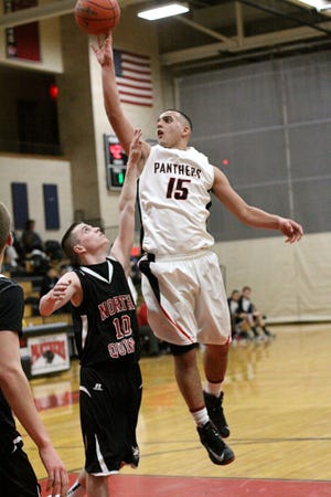 Whitman-Hanson's Brian Feeney goes in for a layup over North Quincy's Pat Gould during a high school basketball game, Friday, Jan. 4, 2013, in Whitman.