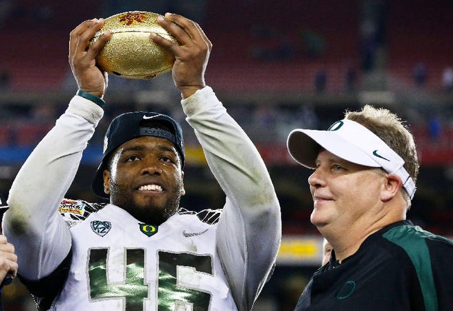 Oregon's Michael Clay, left, holds up the championship trophy as head coach Chip Kelly looks on after the Fiesta Bowl NCAA college football game against Kansas State Thursday, Jan. 3, 2013, in Glendale, Ariz. Oregon defeated Kansas State 35-17.(AP Photo/Ross D. Franklin)