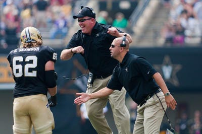 Vanderbilt offensive line coach Herb Hand, center, welcomes one of his players off the field during a game this season.