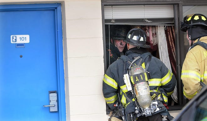 Natick Firefighter Andy Hladick talks to other firefighters from inside the fire-damaged owner's apartment next to the main office of the Travelodge motel on Rte. 9 in Natick on Saturday. The two-alarm fire forced guests to evacuate the motel.