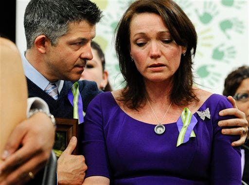 Ian and Nicole Hockley, parents of Sandy Hook School shooting victim Dylan Hockley, listen at a news conference Monday at Edmond Town Hall in Newtown, Conn. One month after the mass school shooting at Sandy Hook Elementary School, the parents joined a grassroots initiative called Sandy Hook Promise to support solutions for a safer community.