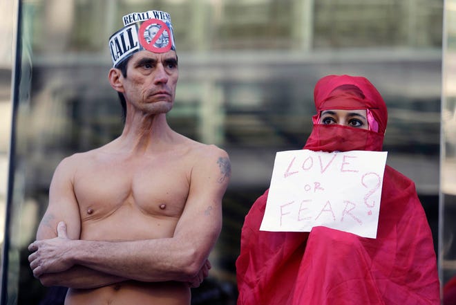 Natalie Mandeau, right, of France, holds up a sign during a demonstration against a nudity ban outside a federal building Thursday, Jan. 17, 2013 in San Francisco. Activists are asking a federal judge to block a city ordinance banning public nudity. The ban is scheduled to go into effect Feb. 1. The local law has become a divisive political issue in a town that prides itself on its inhibitions. The demonstration took place before a court hearing on the ordinance. (AP Photo/Eric Risberg)