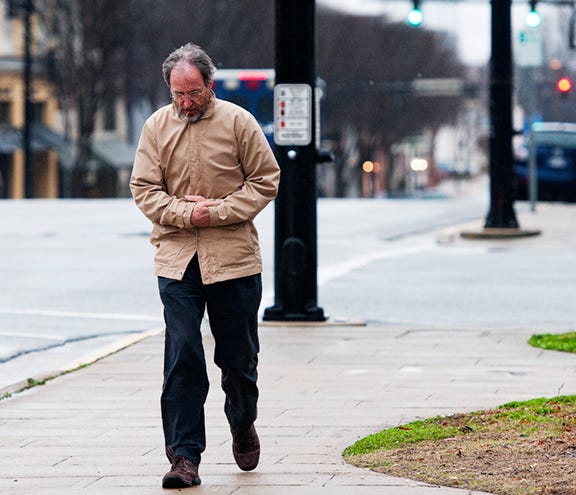 Gavin Rumble keeps his fingers warm in his sleeves while walking on North Main Street in the wind and rain Thursday afternoon.