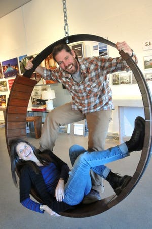 Jeff Soderbergh of Middletown poses with Lisa Randall, the executive director of the Jamestown Arts Center, in a recliner that he built out of reclaimed lumber from the Coney Island boardwalk, which is featured in the center’s Design Expo that opened last Thursday.