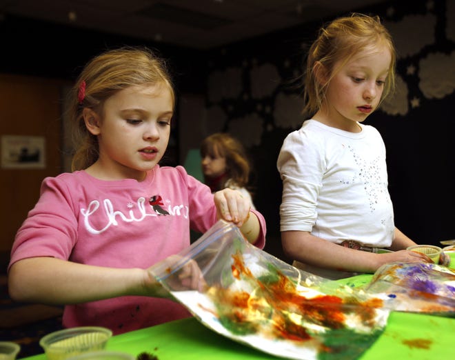 Greta Mansell, 7, and Lydia Stuart, 8, make paintings inside plastic bags during the after-school special story time at the Norman Public Library. PHOTO BY STEVE SISNEY, THE OKLAHOMAN STEVE SISNEY