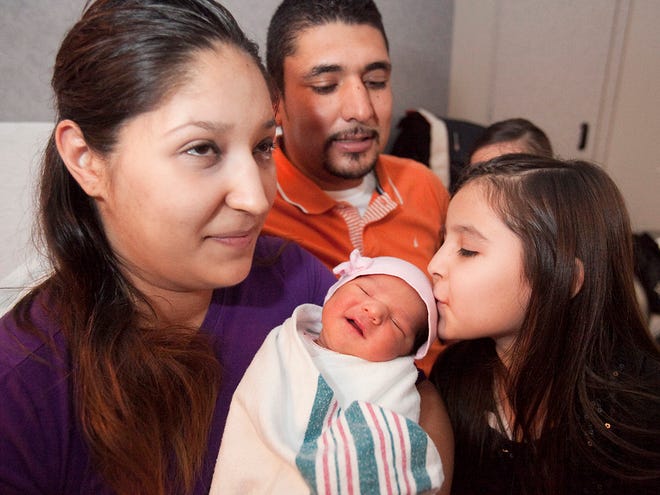 Laura Jimenez holds her daughter Nikole Villasana Jimenez as her oldest daughter Yaqueline Villasana Jimenez, 5, gives her baby sister a kiss on the head as dad, Leobardo Villasana watches in the hospital bed at Munroe Regional Medical Center Friday afternoon.