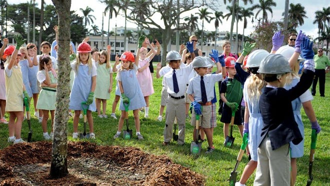 Third-graders from Palm Beach Day Academy, Palm Beach Public School and Rosarian Academy raise their hands after Palm Beach Mayor Gail Coniglio asked, “Who plays outside?” Then they took turns placing soil around a newly planted Tabebuia impetiginosa to celebrate Arbor Day, one day early, at Bradley Park Thursday.