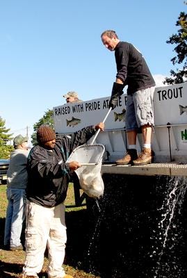 Brian Kubin of the New Jersey Fish and Wildlife Commission hands a net full of trout to Alon Desper of Willingboro to place in Crystal Lake in Willingboro on Tuesday.