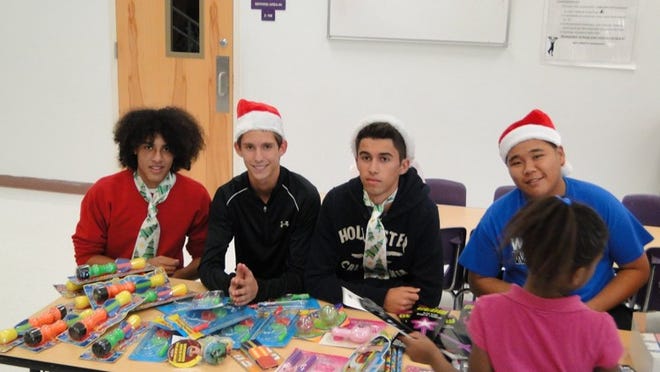 Making their annual holiday visit to Pleasant City Elementary are (from left) Sergio Fedele, Suncoast High; Devin Wallace and Andre Ferreira, Royal Palm Beach High; and Alex Ng, Wellington High. The high school students, who attended Crestwood Middle together, bring donated toys to the youngsters in the after-care program at the elementary school.