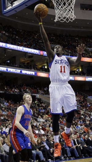 The Sixers' Jrue Holiday (11) drops in a layup as the Pistons' Kyle Singler watches during a victory earlier this season.