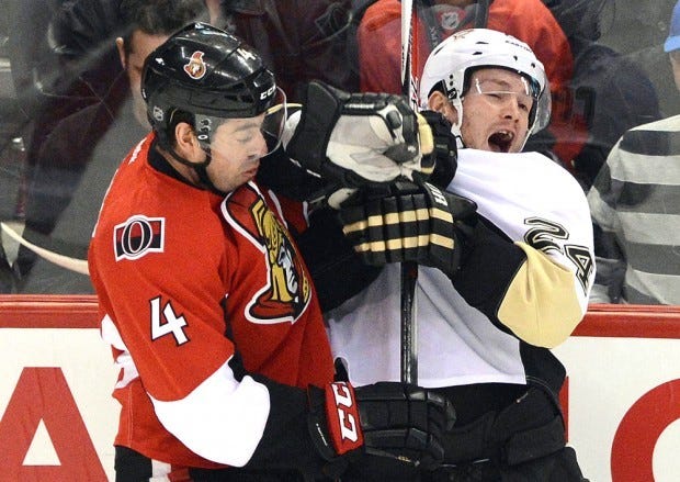 Ottawa Senators' Chris Phillips, left, hits Pittsburgh Penguins' Matt Cooke during second period NHL hockey action in Ottawa on Sunday, Jan. 27, 2013. (AP Photo/The Canadian Press, Sean Kilpatrick)