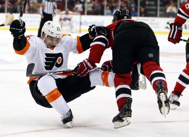 Philadelphia center Scott Laughton (left) is knocked to the ice by New Jersey defenseman Andy Greene during the Tuesday's game.