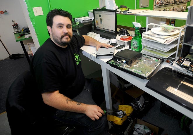 Bryan Harwell, owner of Replay'd in Framingham, repairs, unlocks, sells and recycles phones, laptops, game consoles and other electronic gadgets. Daily News photo by Ken McGagh