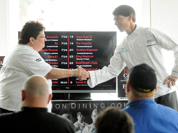 Chef Joanie Babcock of the Faison, N.C., restaurant Southern Exposure, shakes hands with Blockade Runner's executive chef Mark Lawson as the Fire on the Dock competitors are announced Monday.