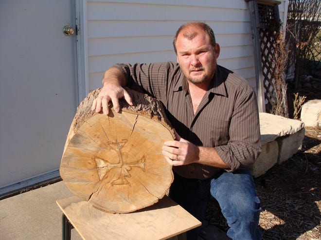 Roanoke resident Tom Durand displays his awe-inspiring discovery. The log appears to contain the shape of a cross with Jesus nailed to the center of it. Durand would find out many more wonders included in the design of the wood over time. It's been 12 years since he first stumbled upon the artwork.