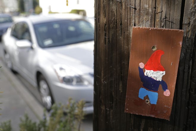 A hand painted portrait of a gnome is shown on a utility pole near Lake Merritt Tuesday, Jan. 29, 2013 in Oakland, Calif. Small paintings of gnomes that have popped up on utility poles have become a community sensation in Oakland, prompting Pacific Gas & Electric Co. to say Tuesday that it will keep them in place for now. The portraits on 6-inch blocks of wood began going up last year in an apparent effort to brighten up the blue-collar California city. There are currently more than 2,000 of the images on utility poles, with many screwed to the bases. (AP Photo/Eric Risberg)