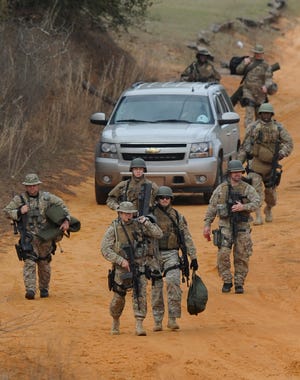 Heavily armed men come back down the hill from the direction of the suspect's home at the Dale County hostage scene near Midland City, Ala. on Wednesday Jan. 30, 2013. Police SWAT teams and hostage negotiators were locked in a standoff Wednesday with a gunman authorities say intercepted a school bus, killed the driver, snatched a 6-year-old boy and retreated into a bunker at his home. (AP Photo/Montgomery Advertiser, Mickey Welsh)  NO SALES