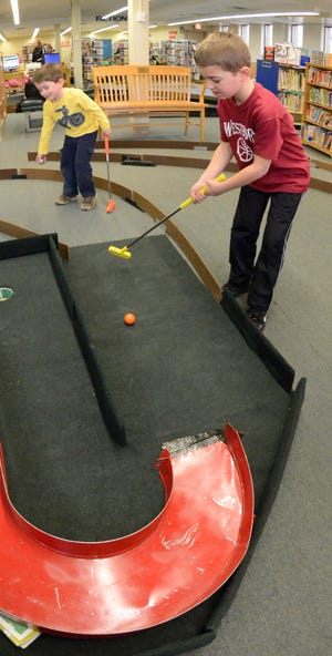 Max Verheijen, 4, gets ready to take his turn while his brother Ben, 7, of Westborough, finishes his putt Saturday at the Friends of the Westborough Public Library's "Masters of Literacy" fundraiser.