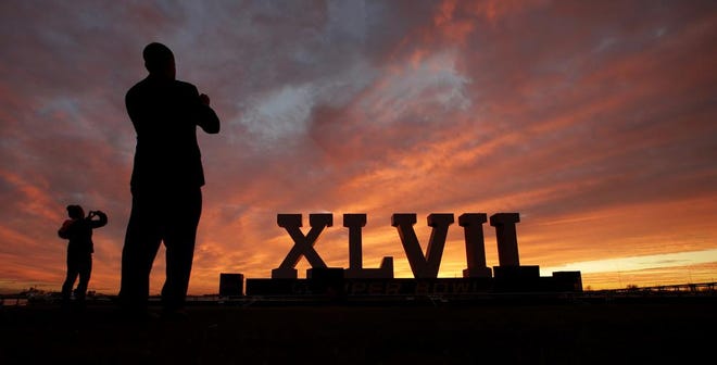 People photograph the Roman numerals for NFL Super Bowl XLVII as they are silhouetted against the morning sky Friday, Feb. 1, 2013, in New Orleans. The city will host the football game between the San Francisco 49ers and Baltimore Ravens.