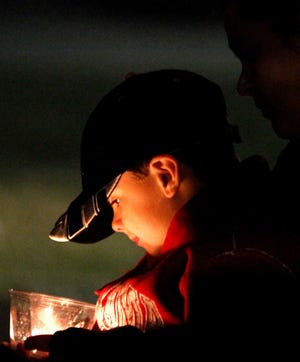 Cole Wyatt watches the candle flicker as he sits with his mom, Sheree Wyatt, as friends gather to pray for a 5-year-old taken hostage, in Midland City, Ala., on Sunday.  Authorities say Jim Lee Dykes, 65 - a decorated Vietnam-era veteran known as Jimmy to neighbors - gunned down a school bus driver and then abducted a 5-year-old boy from the bus, taking him to an underground bunker on his rural property. The driver, 66-year-old Charles Albert Poland Jr., who was shot trying to protect children on his bus, was buried Sunday. (AP Photo/Butch Dill)